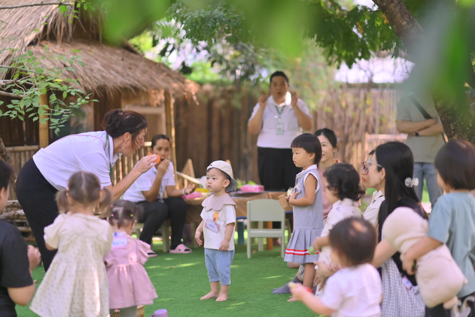 Children and grown-ups gathering with a teacher for playgroup in the garden